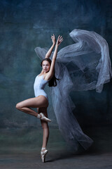 Studio shot of young flexible ballerina dancing isolated on dark vintage studio background. Art, motion, action concept.