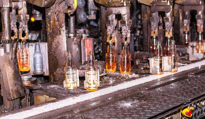 Glass factory, industrial production of glass containers. Modern technology, robots machines make...