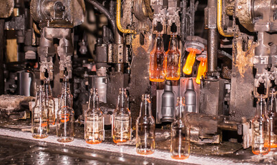 Glass factory, industrial production of glass containers. Modern technology, robots machines make products.Party bottles for drinks. Technological work at the plant. Working atmosphere with copy space