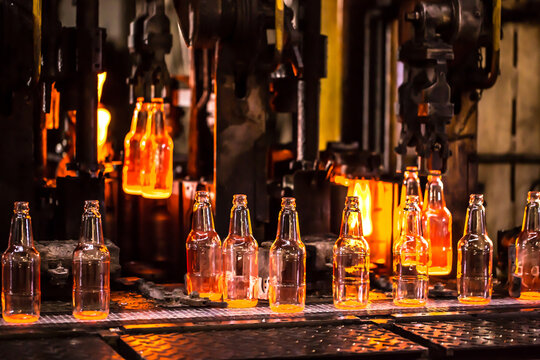 Glass factory, industrial production of glass containers. Modern technology, robots machines make products.Party bottles for drinks. Technological work at the plant. Working atmosphere with copy space