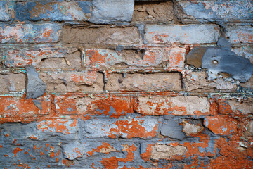 Old, rough brick wall with blue-red cracked paint. Textured background of horizontal brickwork