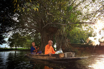 Monk transport by boat pass ancient temple during flood in Ayutthaya Historical Park, Thai Buddhist Monk Rowing Boat pass ancient temple underwater from flooded , Unseen Monk Alms-round receive food