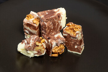 Black and white chocolate fudge with walnuts, isolated on black background. Sweets for Christmas.