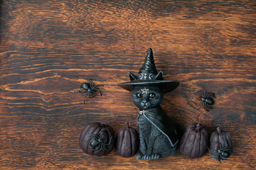 black pumpkins, spiders and witch black cat toy on rustic wooden background. symbol of witchcraft, samhain sabbat and Halloween holiday. fall season. flat lay - obrazy, fototapety, plakaty