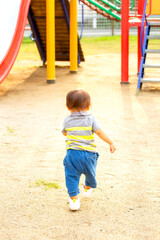 公園の遊具に向かって走っていく幼児
