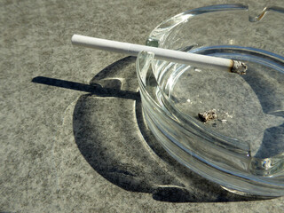 Cigarette in the ashtray with shadow on the desk