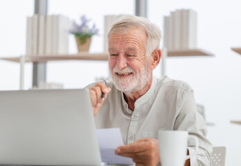 Portrait of senior man using laptop at home, Senior man in living room with laptop browsing internet on modern computer gadget