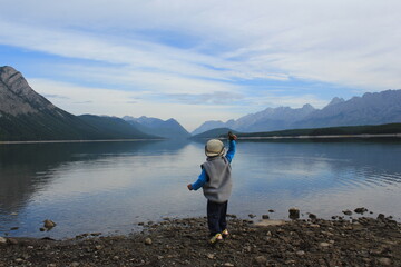 Fototapeta na wymiar ロッキーマウンテンのほとりの湖に石を投げる子供　A kid throwing the rock into the water, Rocky Mountain