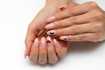 Beige, natural, natural, nude manicure with painted black moon, stars and red heart on long oval nails close-up on a white background.