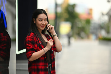Photo of an attractive woman talking on mobile phone while standing in the shopping avenue.
