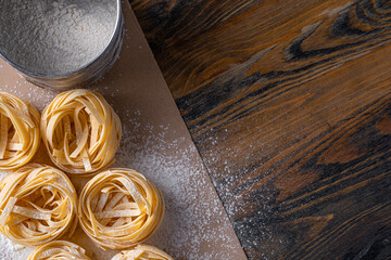 Homemade fettuccine pasta folded in the shape of a nest. Home cooking with ingredients for homemade traditional Italian fettuccine pasta.