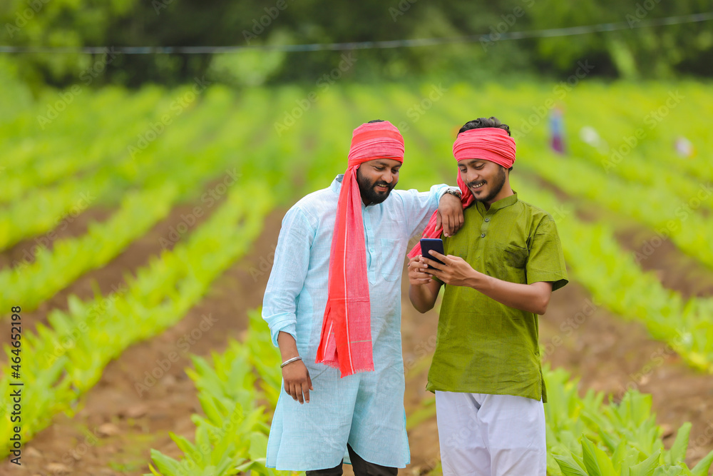 Poster Indian farmer using smartphone at green turmeric agriculture field.