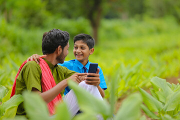 Indian farmer using smartphone with his child at green turmeric agriculture field.