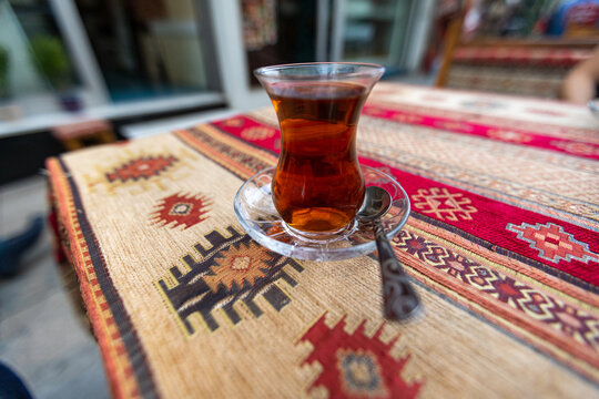 Traditional turkish tea in tulip-shaped glass called ince bellicup on the table of cafe in the historical center of Istanbul. Shallow DOF.