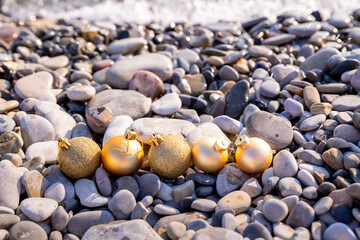 New year at the beach. Christmas ornaments standing on stones near the water.Christmas holiday decorations, balls on a beach at a tropical island during vacation
