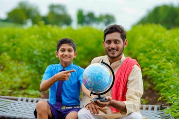 Indian farmer holding world globe in hand and giving some information to his child