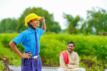 Cute Asian Indian little child wearing yellow construction helmet or safety hard hat.