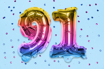Rainbow foil balloon number, digit ninety one on a blue background with sequins. Birthday greeting...