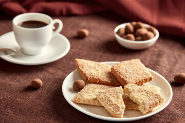 Fototapeta na wymiar Cookies on a white plate. Behind the cookies is a cup of coffee and a bowl of sweets.