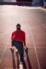 A young athlete in a low start at the race track on the stadium. Sport, athletics, athletes