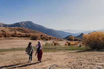 two women tourists are walking along the road among the hills and mountains