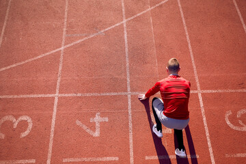 top view of young adult male athlete in low start position at athletic track. start line position....