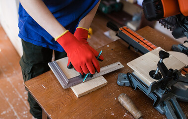 A construction contractor worker measures for cutting boards on a new home construction project....