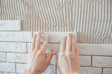 A worker applies tile adhesive to the wall, makes repairs in the apartment. The builder applies the plaster with a trowel. plaster on the wall. stick decorative tiles on the wall