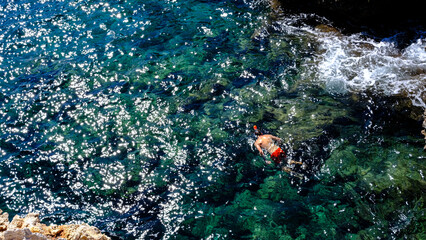 swimmer with mask swims in the turquoise sea of Menorca, Spain