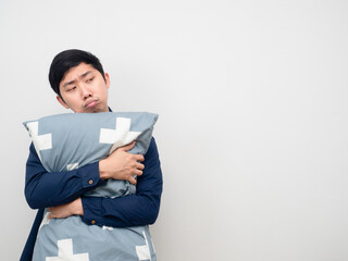 Asian man hug pillow feeling sleepy and bored looking at copy space