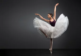 Fotobehang Dansschool Ballerina. Jonge sierlijke vrouw balletdanser, gekleed in professionele outfit, schoenen en witte gewichtloze rok toont dansvaardigheid. Schoonheid van klassiek ballet.