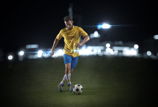 A professional soccer player demonstrates complex moves in the soccer arena wearing a yellow jersey and blue shorts.