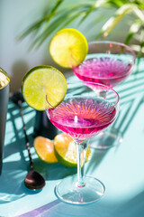 A pair of cocktail glasses with campari decorated with lime slices.