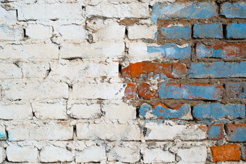 Textured grunge background. Brick wall with white and blue paint outdoors. Old, cracked horizontal brickwork with copy space for text