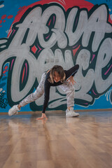 Obraz na płótnie Canvas Attractive young woman doing breakdance move over graffiti background