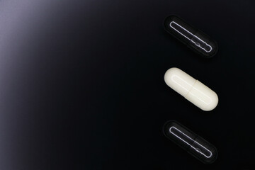 Black And White Gel Pill Capsules On Smooth Black