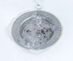 A stream of water flowing down the drain in the sink