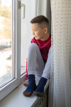 a little boy sits on the windowsill and sadly waits for someone