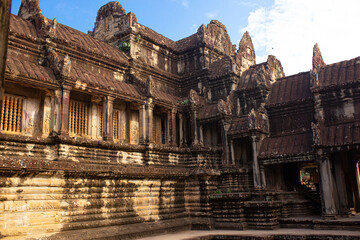 Fototapeta na wymiar The ancient city of Angkor Wat in Cambodia. Towers of the temple of the Kmer people streets and ruins of houses. Traveling to the sights of ancient civilizations. Stone bas-reliefs on the ruins.