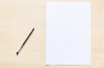 top view of plastic pen and blank sheet of white office paper on light brown wooden board