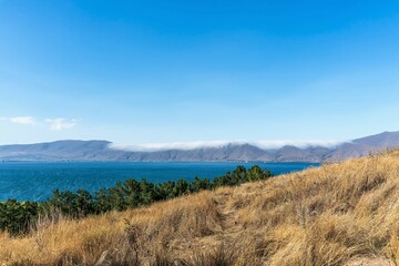 Armenia, Lake Sevan, September 2021. Sun-burnt grass on the slope and a view of the lake.