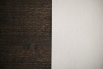 Half of white paper on a dark wood texture background. Vertical separation.