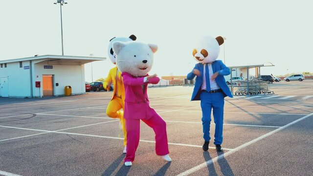 Happy people wearing a panda giant head dancing and having fun in a parking lot