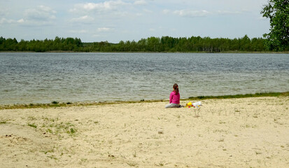 Plaża i dziewczynka siedząca na piasku.  - obrazy, fototapety, plakaty