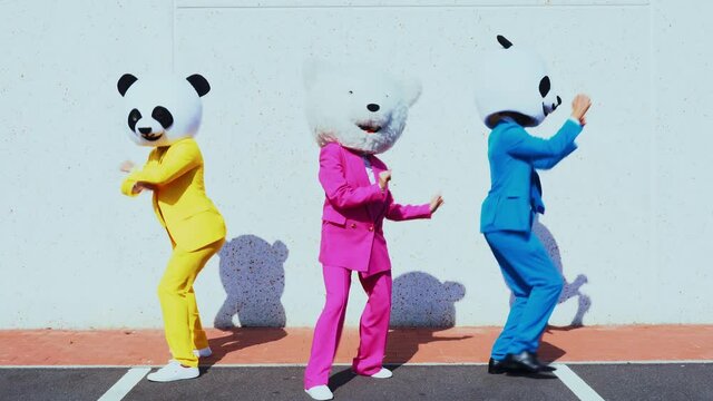 Happy people wearing a panda giant head dancing and having fun in a parking lot