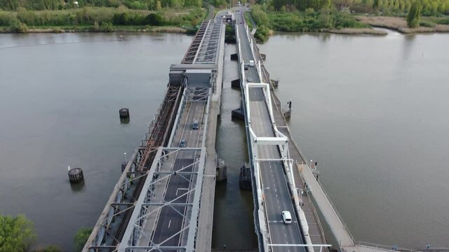 Temse bridge over the river Scheldt seen from above with traffic and cars driving on both side of the road near green trees in summer. Drone aerial bird eye view reveal shot