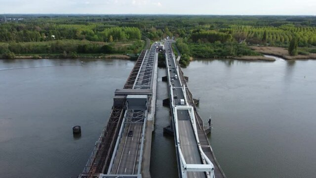Temse bridge over the river Scheldt seen from above with traffic and cars driving on both side of the road near green trees in summer. Drone aerial bird eye view shot