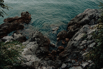 View from above of a rocky cliff on the shore and the blue sea water in Croatia.