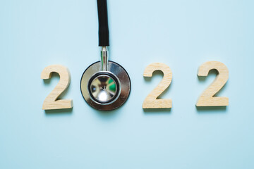 hand holding Stethoscope with 2022 number on blue background. Happy New Year for healthcare,...