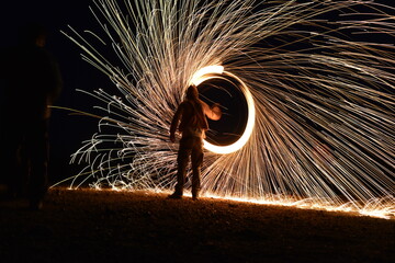 Iron wool circle drawing light fireworks. Burning Steel Wool spinning, Trajectories of burning sparks at night. Movement light effect, steel wool fire hoop. long exposure light painting, Pyrotechnic